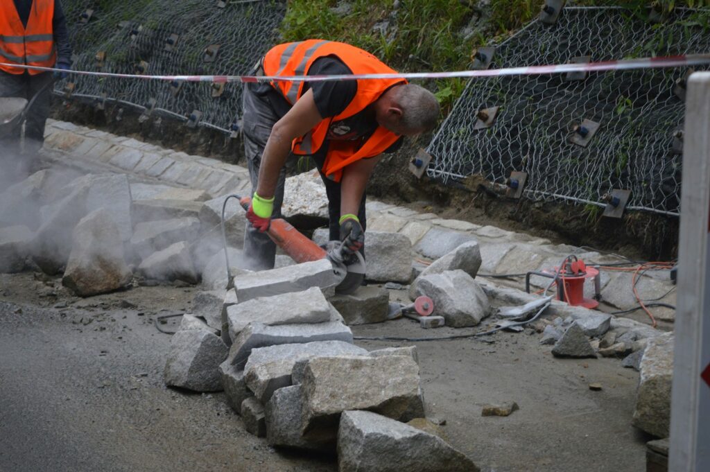 Construction worker using an angle grinder to cut stone blocks